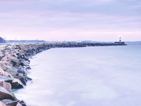 Shinning lighthouse at the end of stony pier. Cloudy eveningafter rainy day, Sassnitz, Germanyの写真素材