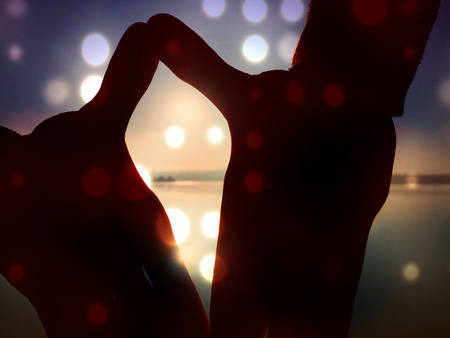 Abstract, over filtered. Hand shadowplay symbol. Hands in the air along beach with the sunrice sky in background.の写真素材