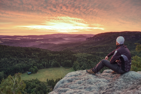 Fearless hiker man in sportswear sitting on cliff edgeの写真素材