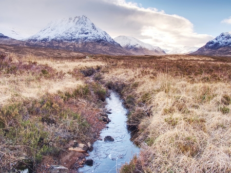 Rounded mountains peak against to cold river. Scotland highlands landscape within early spring.の写真素材