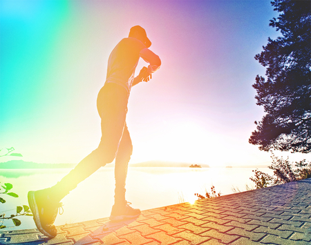 Abstract, over filtered. Sports man stretching body after running workout outdoors on beach at...