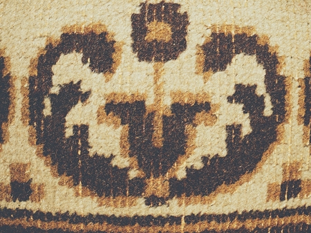 Closeup surface fabric at old carpet texture. Worn places with faded flowersの写真素材