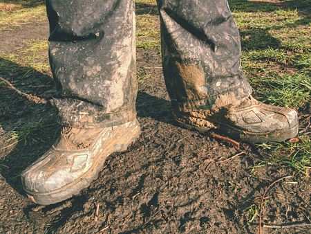 Farmer wearing muddy boots in daily business. Muddy rubber boot in horse farm area
