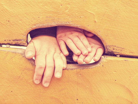 Kid climbing hand in hole of outdoor climbing wooden wall. Selective focus on the hand.の写真素材