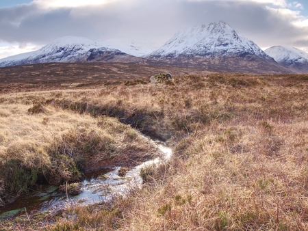Rounded mountains peak against to cold river. Scotland highlands landscape within early spring.の写真素材