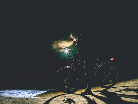 MTB cyclist stop the Bike on frozen lake in the Night and check the paper map. Extreme orienteering bike raceの写真素材