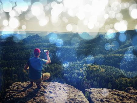 Man hiker sitting on a rock in mountain. Abstract, over filtered. Man sit. Fall mountain mist. Mist in valleysの写真素材