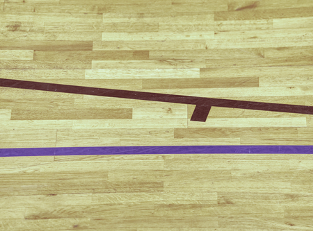 Black lines in play court on wooden lamino floor. Worn out brown wooden floor panels of sports hall