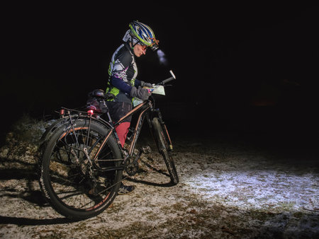 Winter night extreme bike racer control navigation and the map.  January 25th 2019, Novy Bor, Czech Republic. Outdoor orienteering check point activity. Extreme night cyclist competitionのeditorial素材