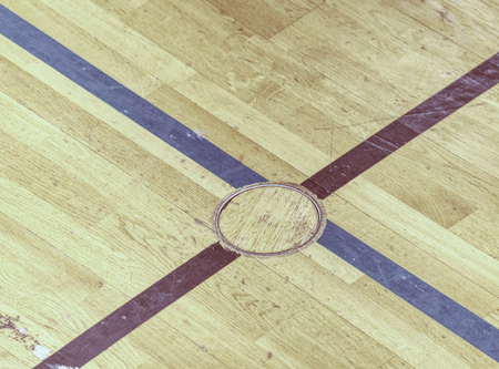 Protection circle cap of a electrical outlet in wooden floor. Painted lines on wooden floor of sporting hall with sratched surface.の写真素材
