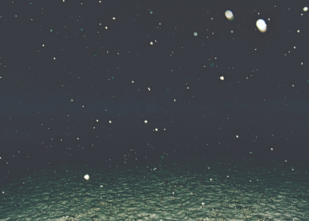 Snowfall within dark new year night. Winter background