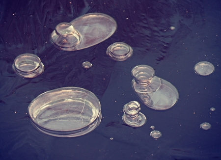 Bubbles frozen in thin ice. Colorful piece of ice with sun rays reflections. Abstract ice texture.の写真素材