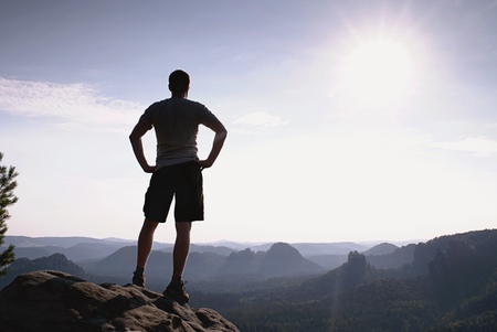 Self confident hiker in akkimbo pose on the peak of rock in rock empires park and watching over the misty and foggy morningの写真素材