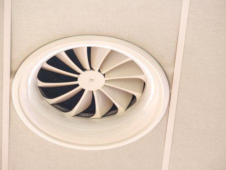 One large painted metal furnace air vent grill with many openings on a ceiling cの写真素材