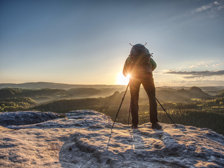 Artist set camera and tripod to photograph the sunrise on a rocky summit. Artist works in natureの写真素材