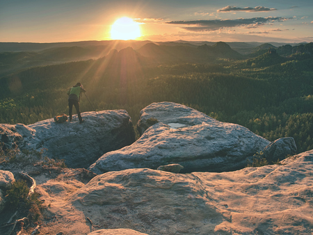 Amateur photographer prepare equipment for taking photos with tripod and  mirror camera . Dreamy foggy landscape spring orange pink misty sunriseの写真素材