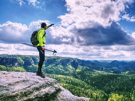 Tourist in yellow green black sportswear and green backpack stay on view point and watch spring landscape.の写真素材