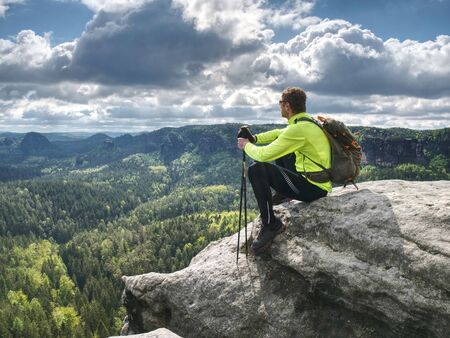 Ultralight runner on trail with tracking poles. Tired sitting tourist with trekking poles in hand. Sunny Spring Morning in Sandstone Rocksの写真素材