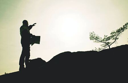 Man traveler holding map in hands plan way outdoor on hilly landscape background. Summer vacations and map travel man lifestyle concept. Man holding a paper map in handsの写真素材