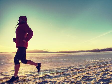 Fitness people, sport and healthy lifestyle concept - young woman in sport suit running along ice covered winter river.の写真素材