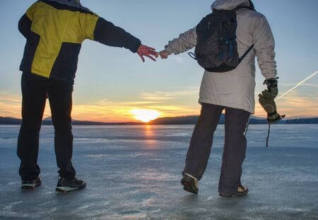 Couple, man and woman walking on the ice on a frozen lake. Happy couple on a frozen lake on a winter dayの写真素材
