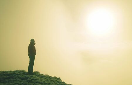 Sporty man on mountain peak looking on mountain valley with low mist at colorful sunset in autumn.