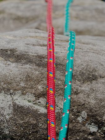 Nylon rope on gray rocky background. Climbing equipment. Twisted old fashion rope fixed on rock....
