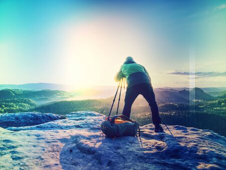 Artist set camera and tripod to photograph the sunrise on a rocky summit. Artist works in nature. Abstract filter.の写真素材