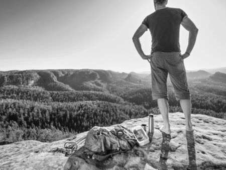 Man with lunch box on cliff at sunset time, sun rays on background without cloudsの写真素材
