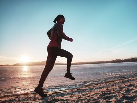 Slim body person is running. Beach sand with many footprints glittering under jumping body.の写真素材