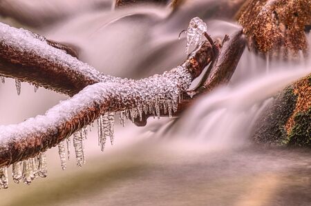 Icicle on the rocks an trunks, winter at river