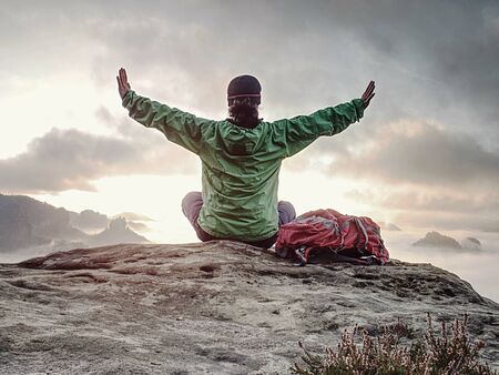 Woman just enjoying the life. Beautiful girl backpacker sitting on top of the mountain and enjoying...