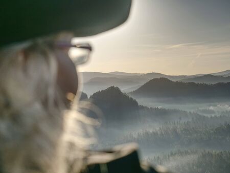 Pretty hiker backpacker sitting on the peak edge and enjoying mountains view valley during high altitude trekの写真素材