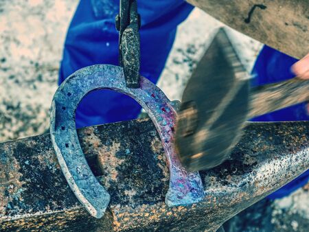 Blacksmith Forges Hot Horseshoe. Farrier is making horseshoe hitting a hammer on the anvil