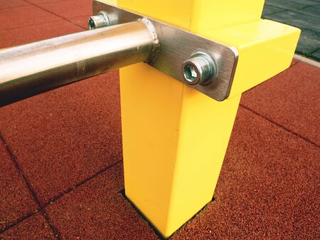 Screwed yellow workout construction on outdoor playground. Steel pole with beam and chrome...