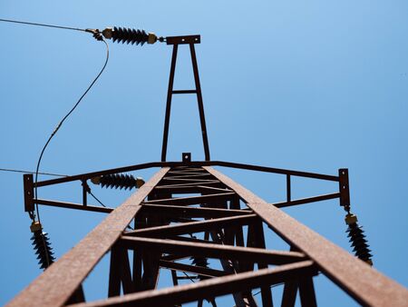 Old rusty construction of high-voltage pole against the sky, high voltage.