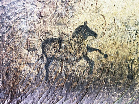 Abstract children art in sandstone cave. Black carbon paint of horses on sandstone wall, copy of prehistoric picture.の写真素材