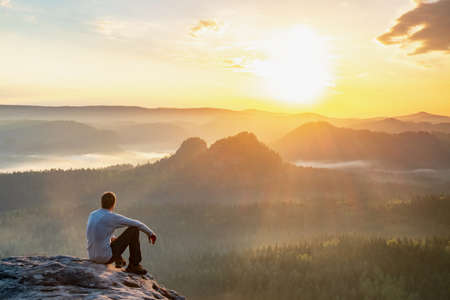 Alone hiker man sitting on a rock and enjoying spectacular view. Pure natureの写真素材
