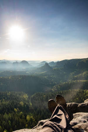 Tired lone tourist sitting on the edge against the backdrop of an incredible mountain landscapeの写真素材