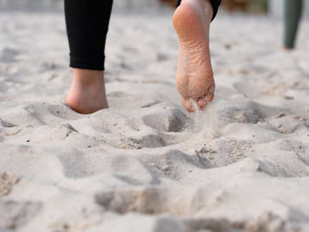 Moving feet and legs of a female teenager beach volleyball player. White sand on outdoor court.の写真素材