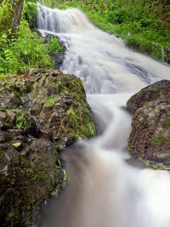 Bright autumn colors in rapid stream. Wave over mossy stone in path ford of mountain stream.