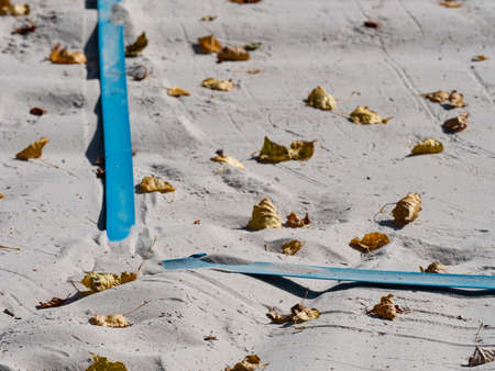 Fallen autumn leaves on the white sand of beach volleyball court in a park in the autumn