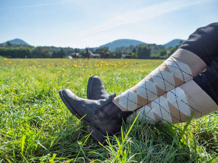 Woman horse rider sit with crossed legs in horse paddock boots and long tights. Horse farm and equestrian sports eventsの写真素材