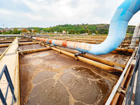 Pipe and walk bridge above waste water pool. Sedimentation tank in a sewage treatment plant