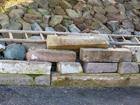 Granite blocks in pile. Rebuilding of old house and basement. Old wooden ladder.