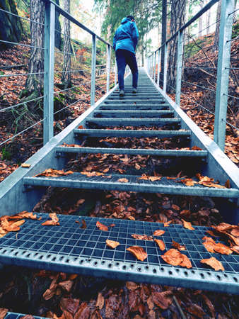 Boy climbs an outdoor steel staircase to the rocky viewpoint of the ruins of a fortress from thirteenth centuryの写真素材