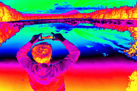 Sportsman in sweatshirt and shorts hold phone in hand at lake. Gamma radiation spectrum in simulator.の写真素材