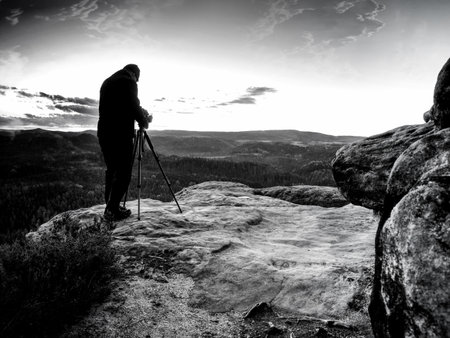 Man with camera making photo on a hill at sunset and clouded sky. Abstract filter.の写真素材