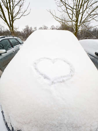 Big lovely heart drawn in the snow on car. Fresh powder snow.の写真素材