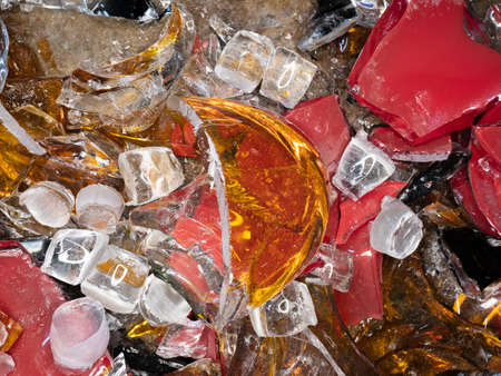 Stained glass shards and waste in a glass studio container. The hot glass is cut with special...